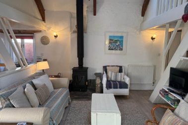 The sitting room has comfortable seating for six. There is a logburning stove and a smart TV.