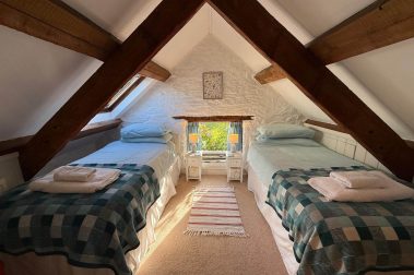 The twin mezzanine bedroom (above the bathroom) overlooks a garden and is cosy, with a sloping beamed ceiling.